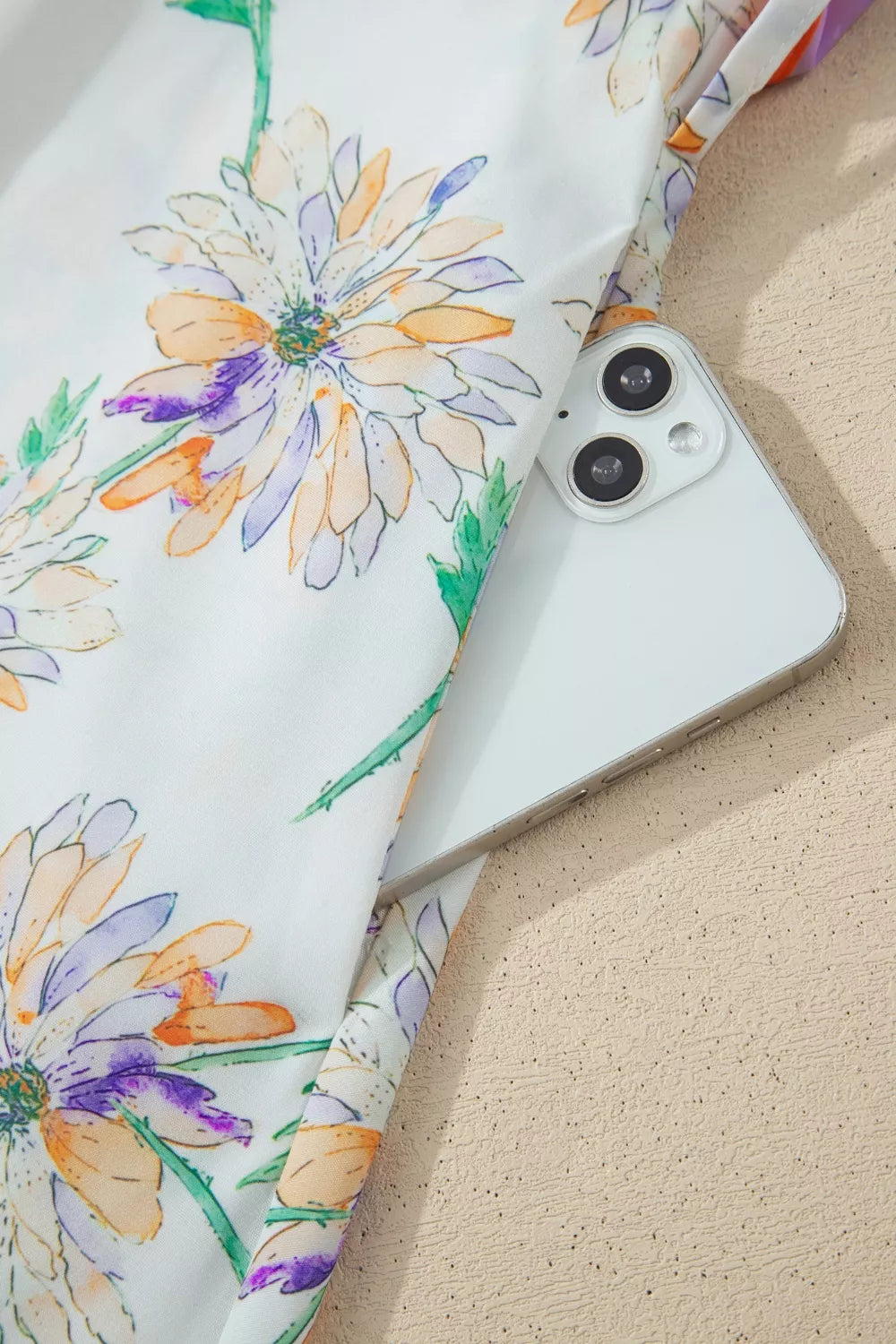 Floral print belted sleeveless dress with a white background and purple, orange, and green flowers.
