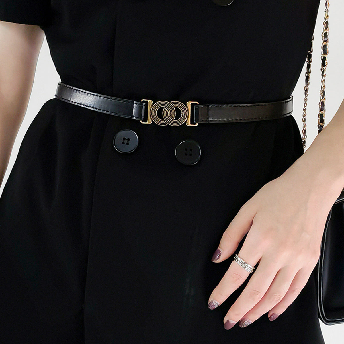 Black vegan leather belt with interlocking gold buckle detail.