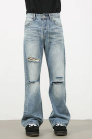 Distressed flare-leg denim jeans in medium wash with ripped details.