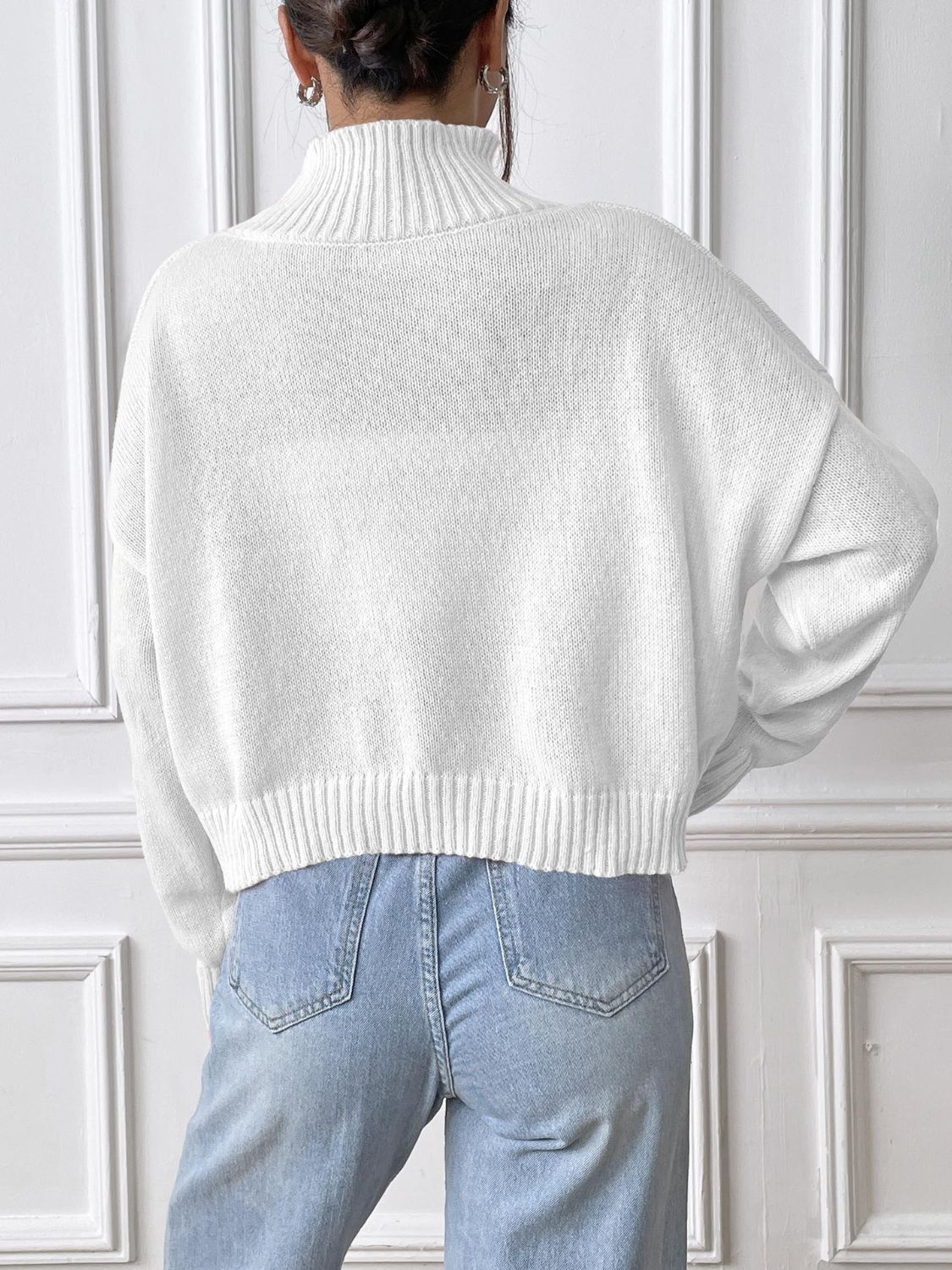 White knit turtleneck sweater with lace appliqué detail and ribbed cuffs and hem.