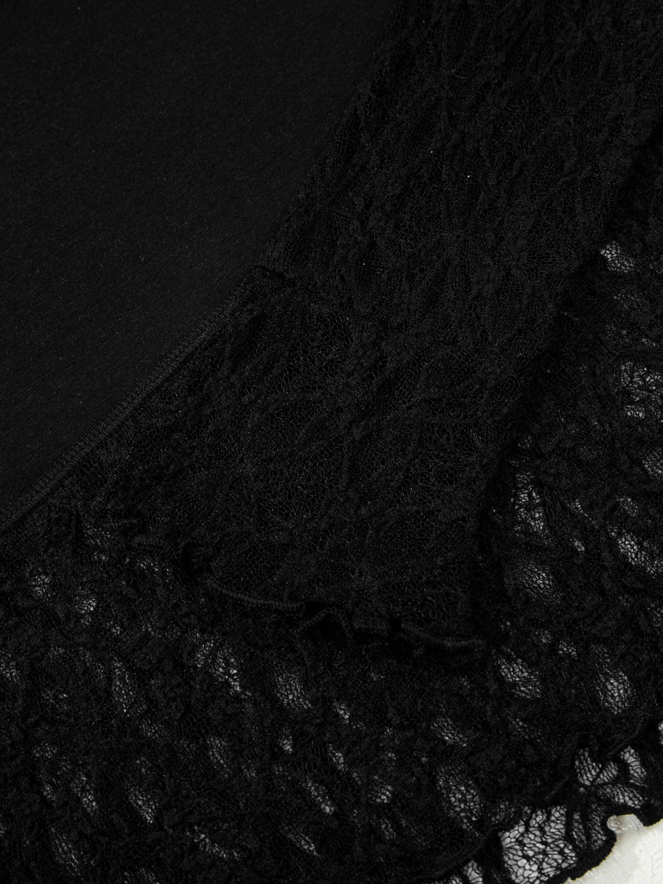 Black sheer blouse with lace trim detail and asymmetric hem.