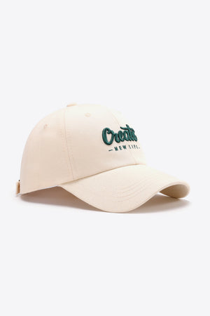 Ivory baseball cap with green embroidered "Create New Life" text.