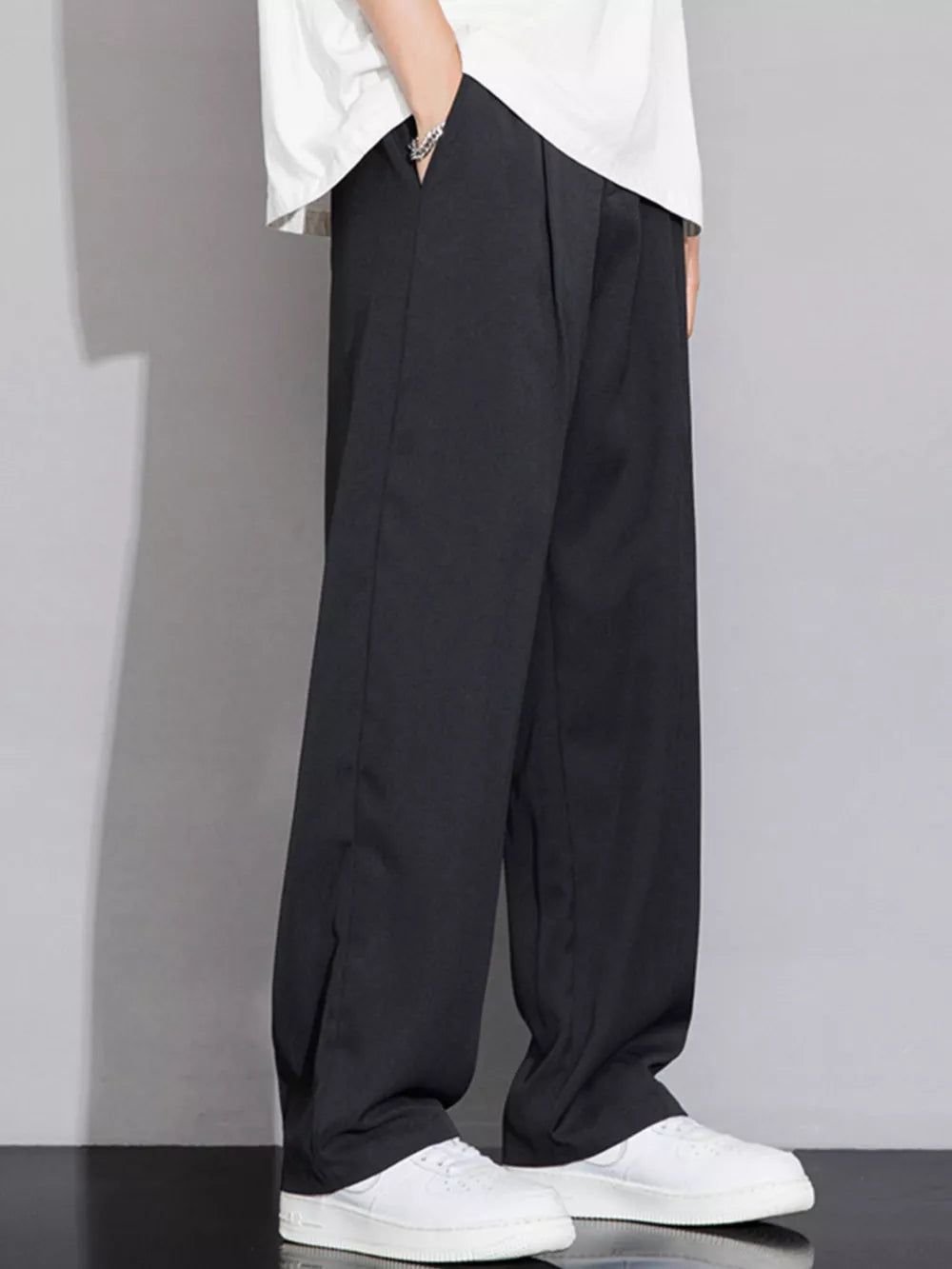 Men's black wide-leg chinos with a relaxed fit, styled with white sneakers.