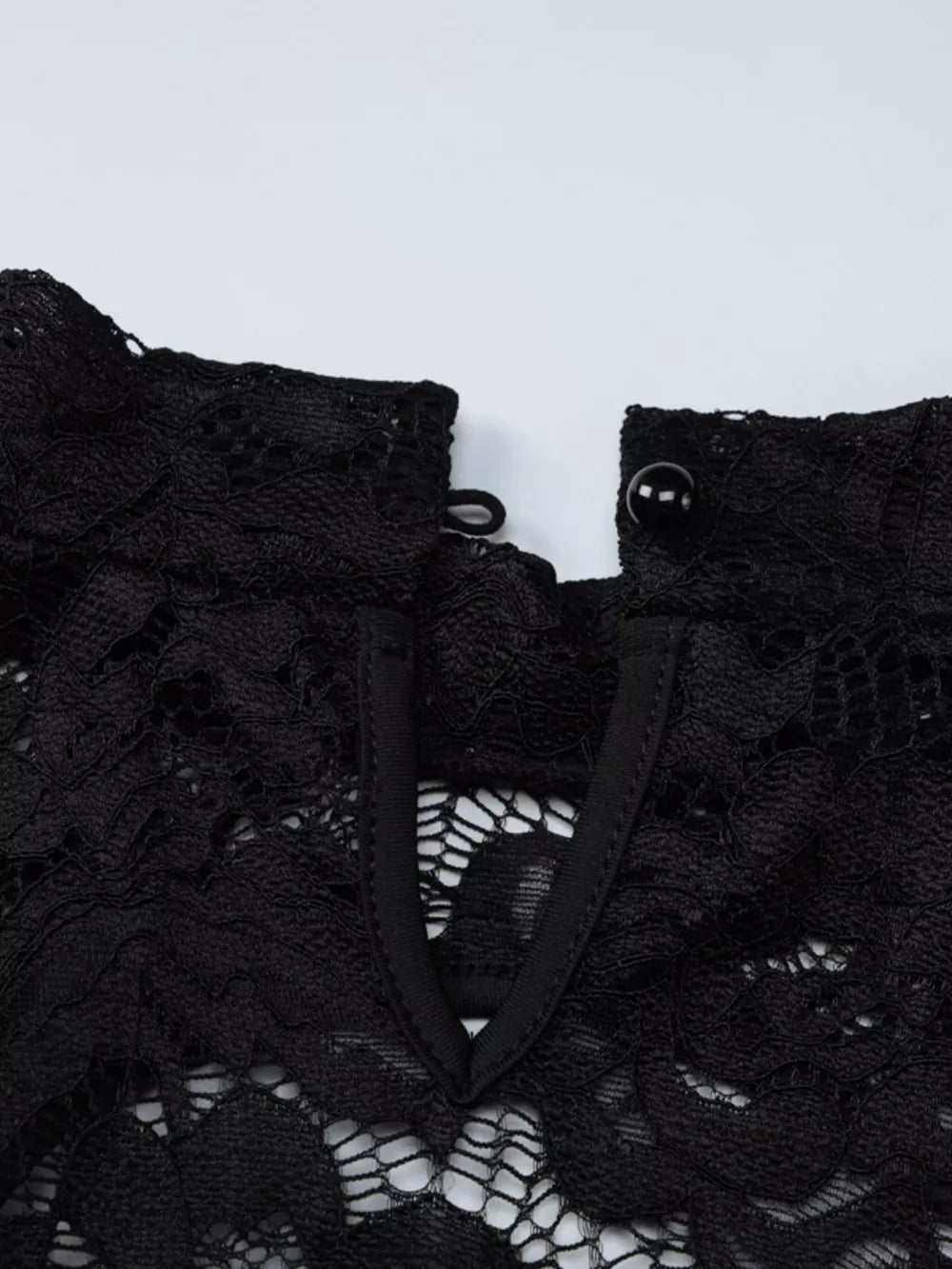 Black lace mini dress with cutout detail and button closure at the neck.