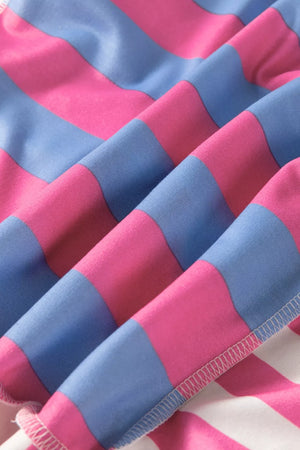Oversized maternity shirt with bold pink and blue stripes and visible zigzag hem detail.