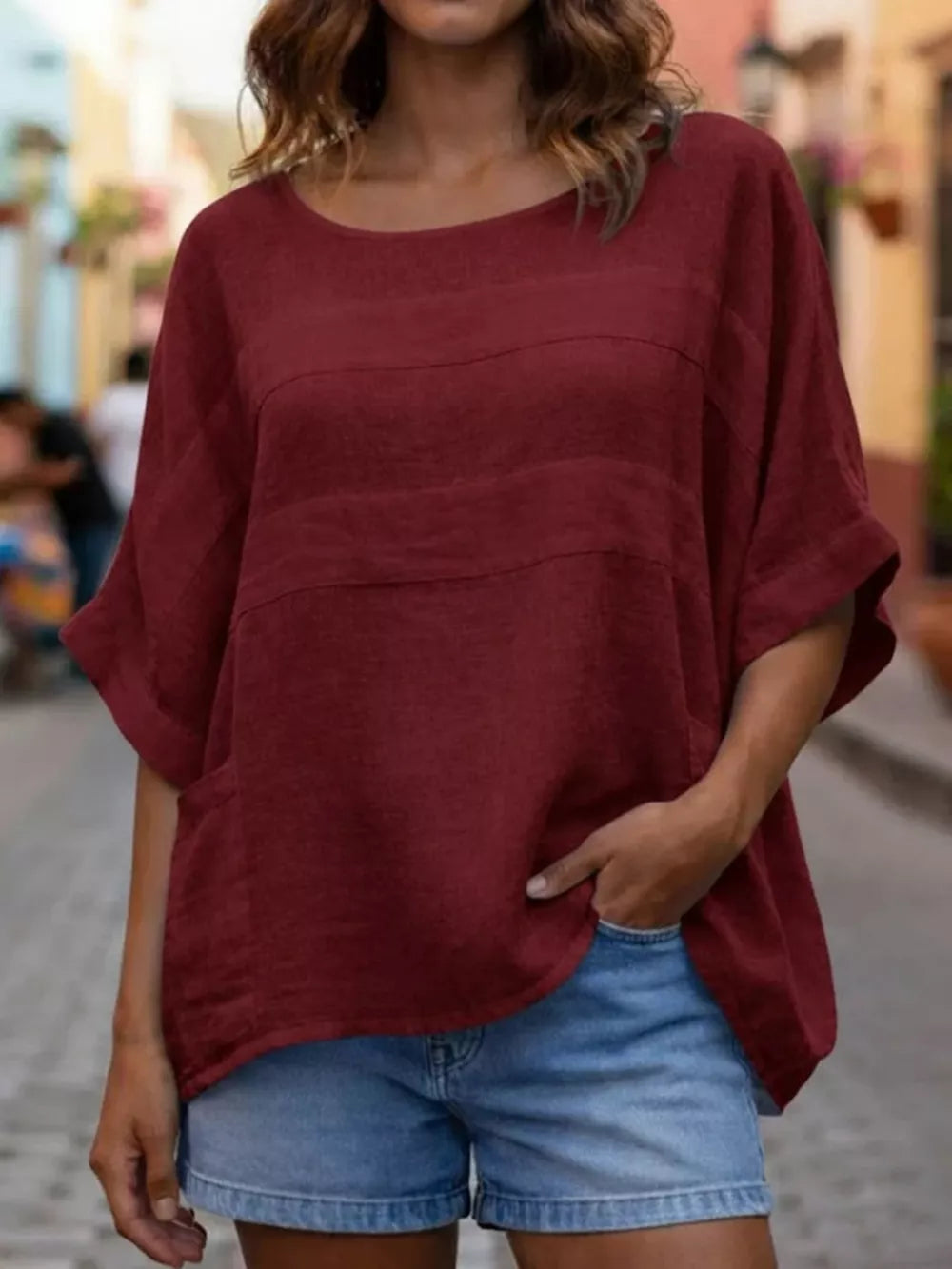 Wine red relaxed fit blouse with horizontal seam details and short sleeves.