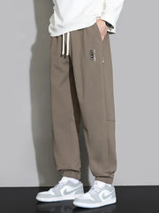 Brown men's joggers with cuffed ankles and subtle logo detail.
