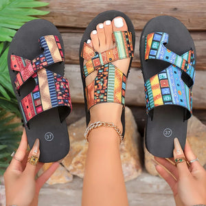 Toe loop sandals with colorful geometric pattern straps and black soles.