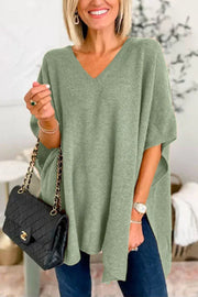 Sage relaxed V-neck knit poncho top with side slits, styled with a black quilted handbag.