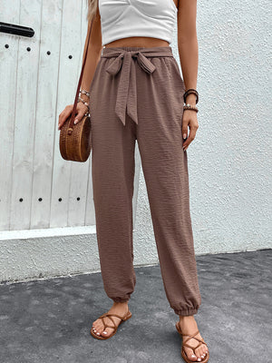 Brown textured tie-waist jogger trousers with cinched ankles.