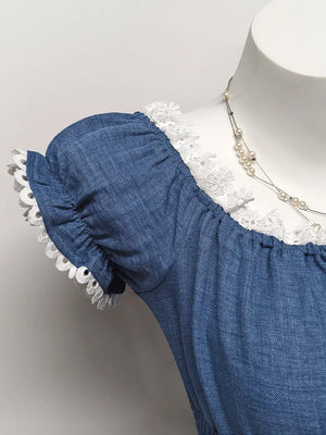 Blue denim maternity blouse with smocked neckline, puff sleeves, and eyelet trim.