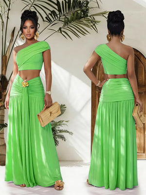 One-shoulder ruched crop top and maxi skirt set in bright green with a gold floral detail at the waist.