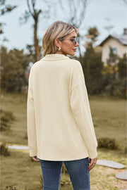 Ivory textured cable knit polo top with long sleeves and a collared neckline.
