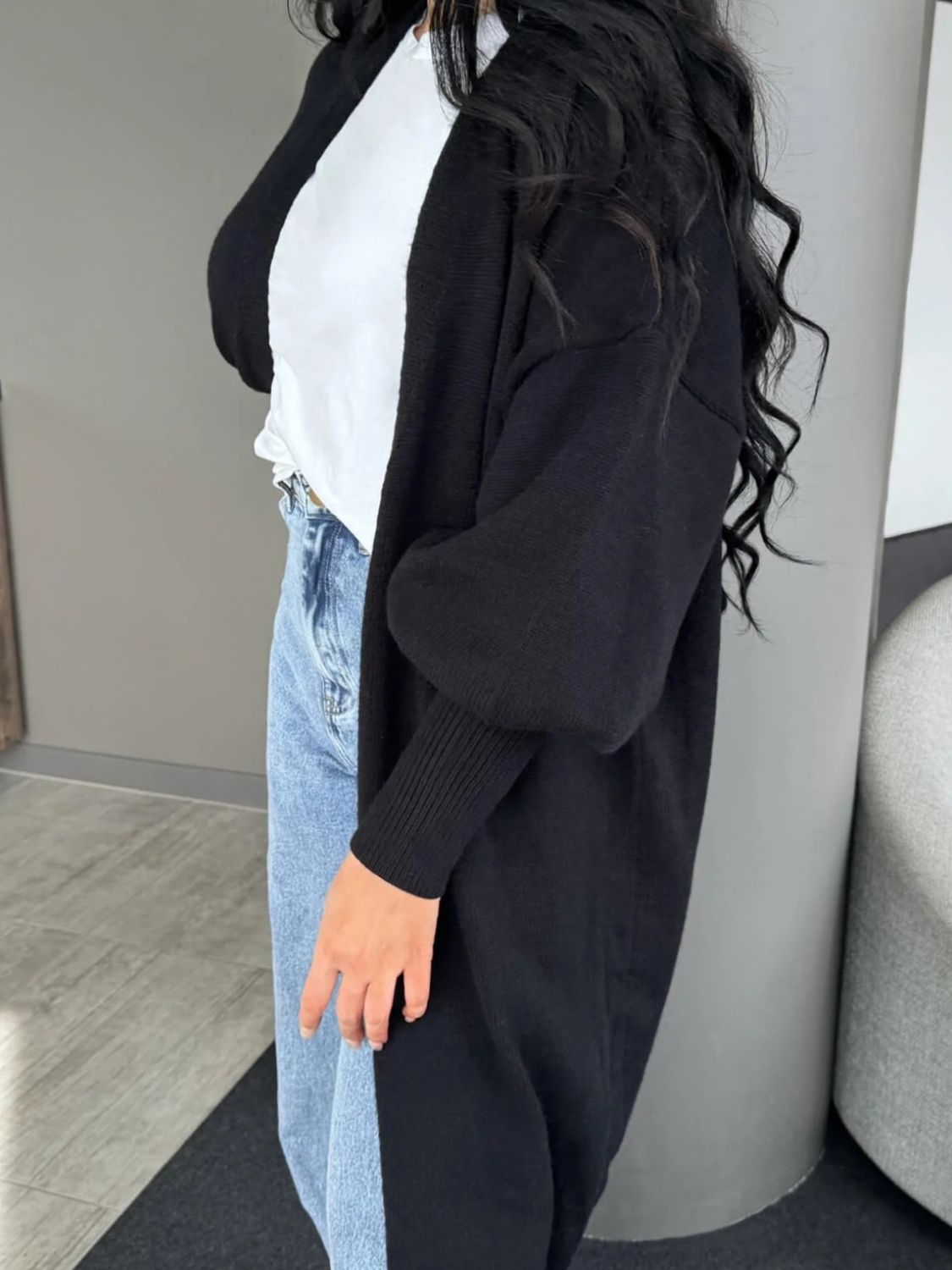 Black acrylic maxi cardigan with balloon sleeves and ribbed cuffs.
