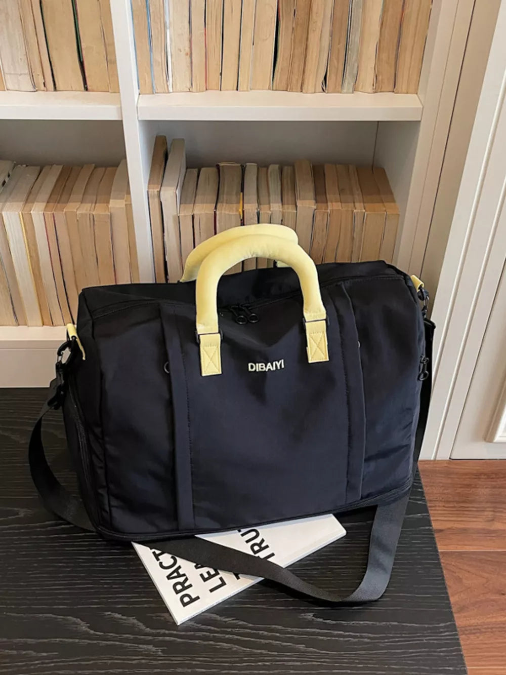 Black nylon travel duffel bag with padded yellow handles and detachable strap