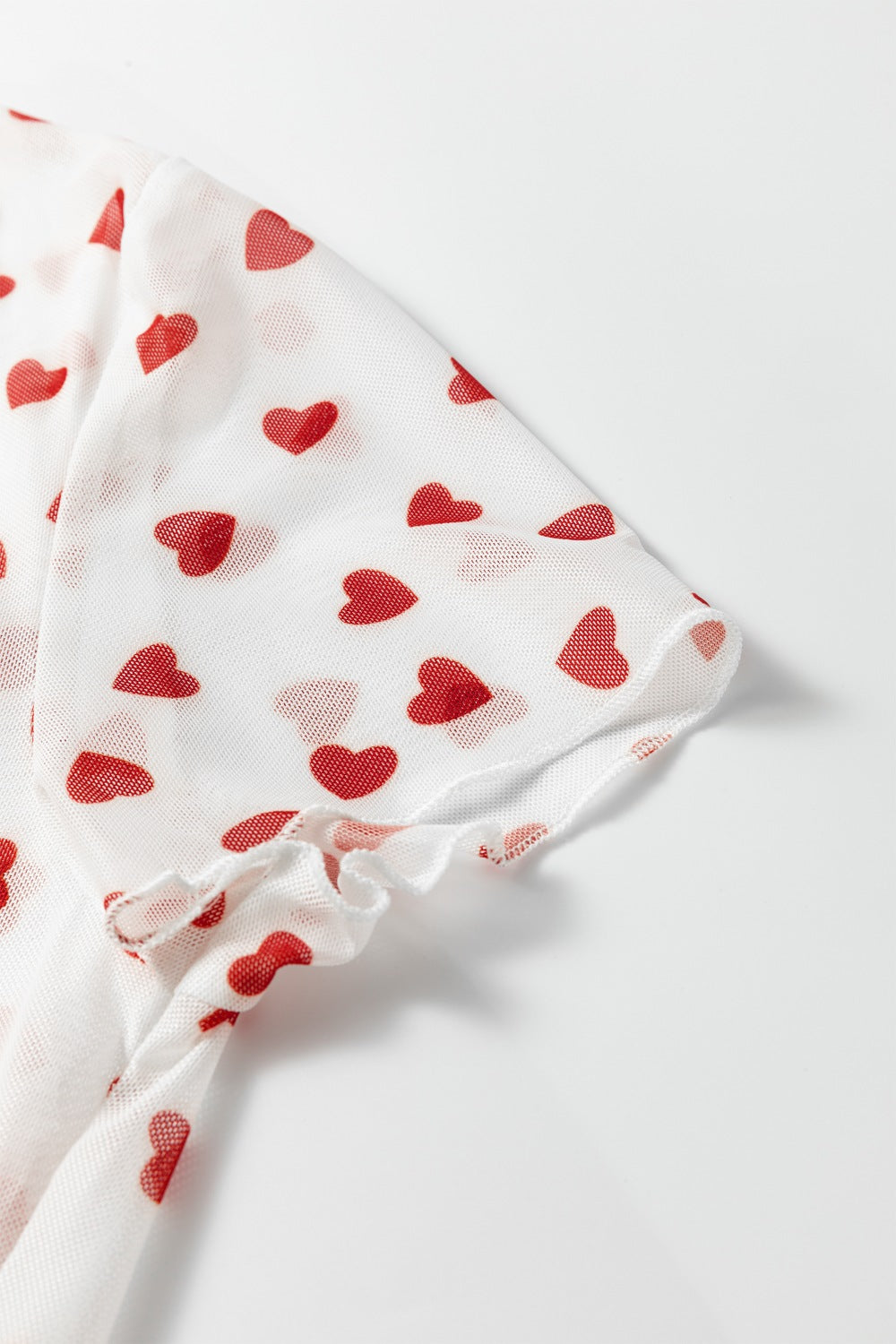 White mesh t-shirt with red heart print and ruffled sleeve hem.