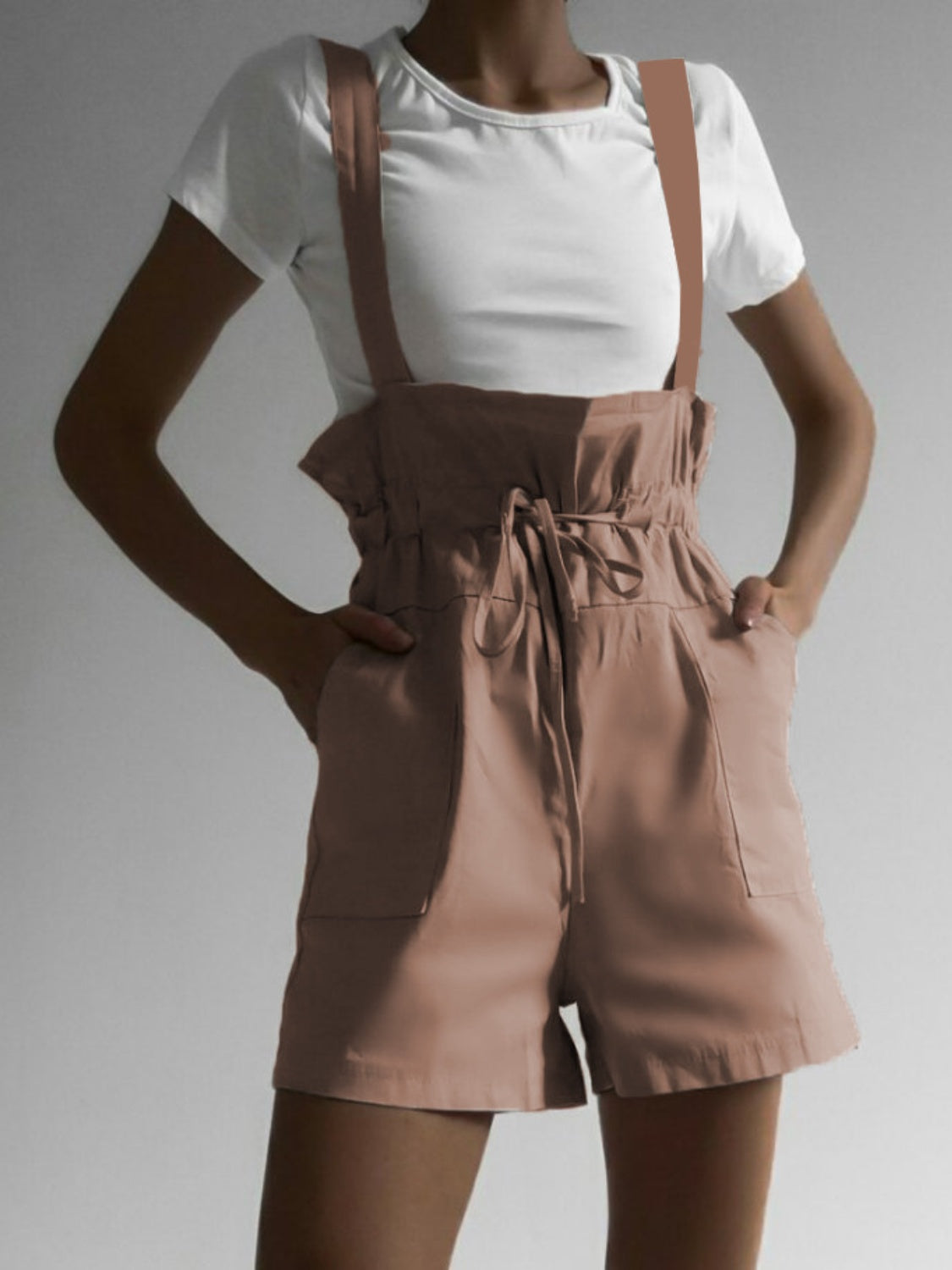 High-waisted drawstring suspender shorts in dusty pink with a paperbag waist and side pockets.