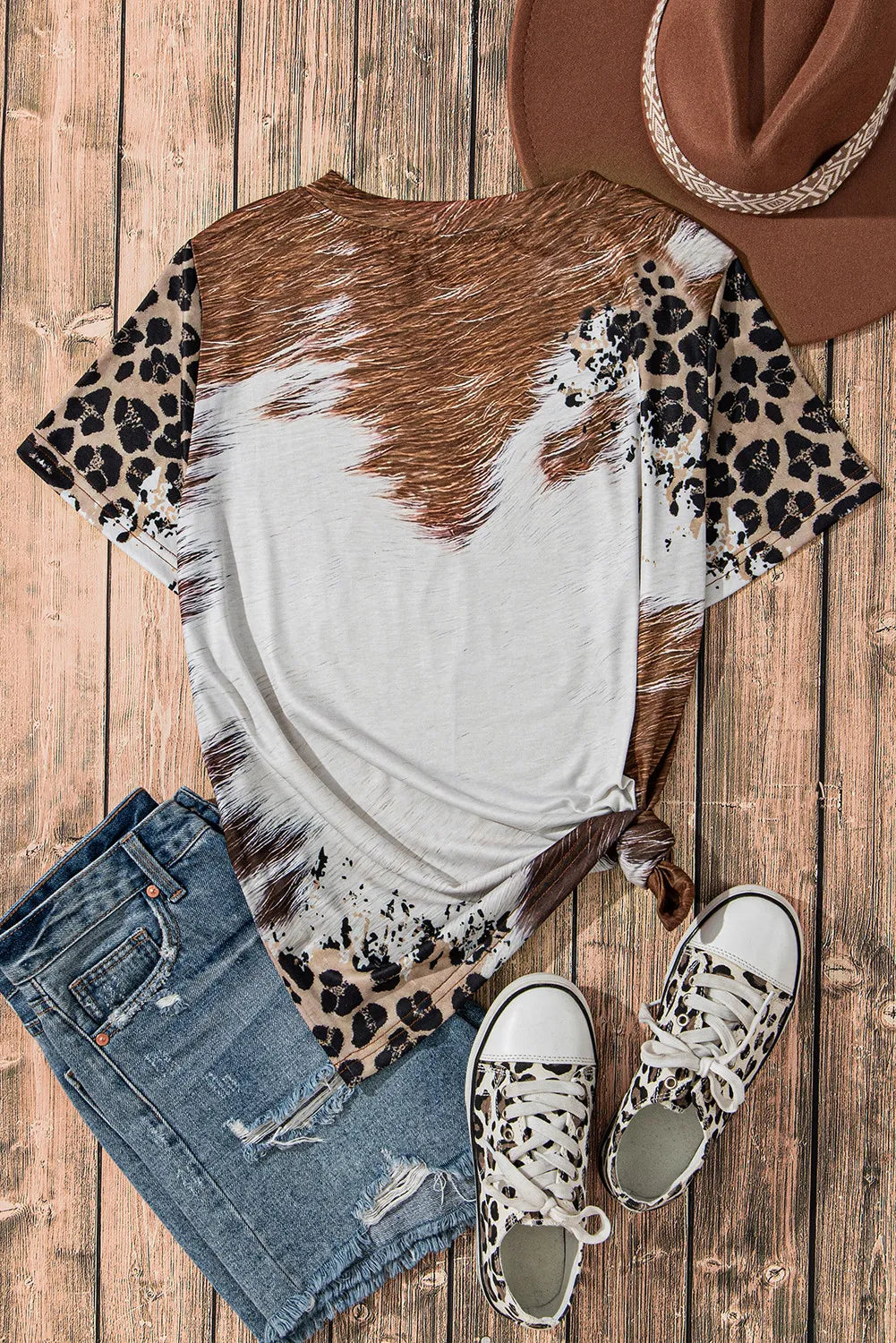 Cowhide print t-shirt with leopard print sleeves, crew neck, and knotted hem.