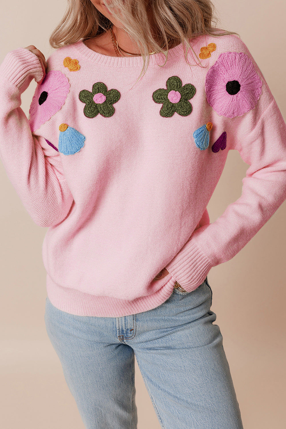 Blush pink knit sweater with embroidered floral appliqués and crewneck.