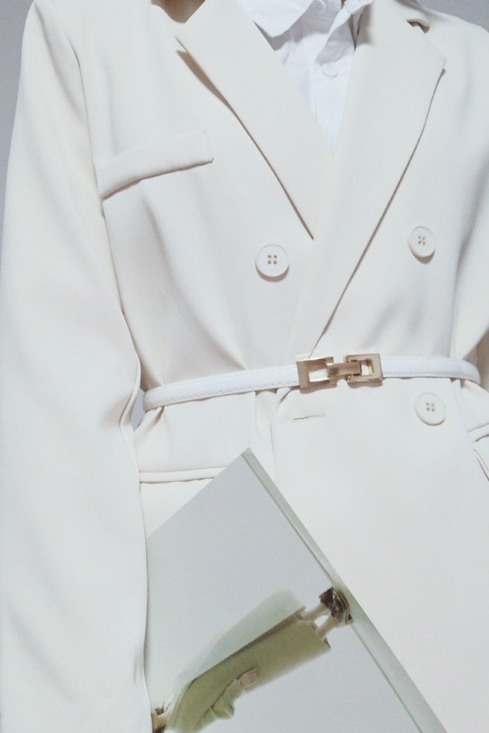 White leather belt with gold geometric buckle, styled with a cream blazer.