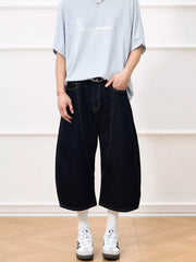 Oversized cropped dark navy denim shorts with balloon cut and visible stitching.