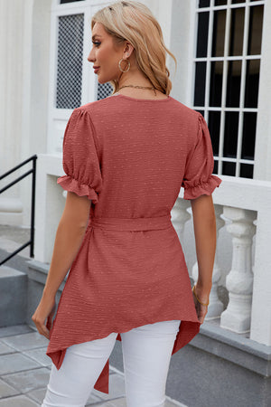 Dotted Swiss asymmetric hem blouse in watermelon pink with puff sleeves and tie waist.