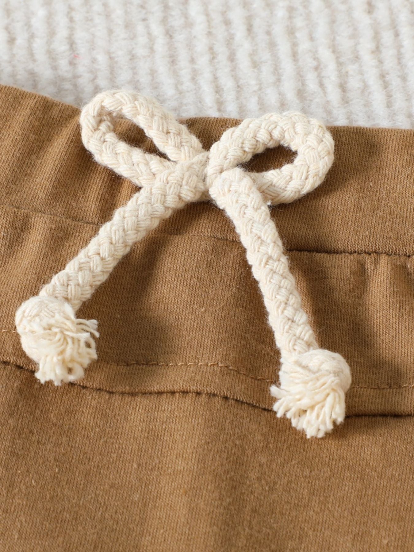 Khaki cotton baby set detail with a cream braided drawstring and frayed ends.