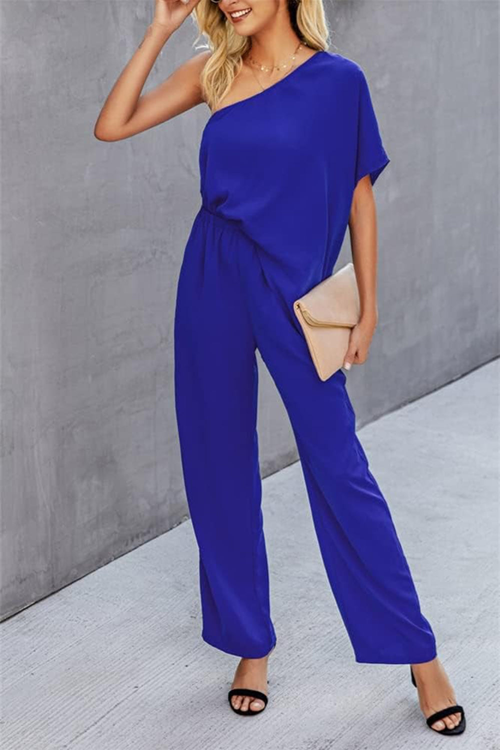 Royal blue asymmetric drape-sleeve wide-leg jumpsuit with elastic waist and wide legs.