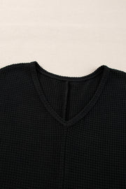Black waffle knit V-neck top with a subtle slit detail at the neckline.