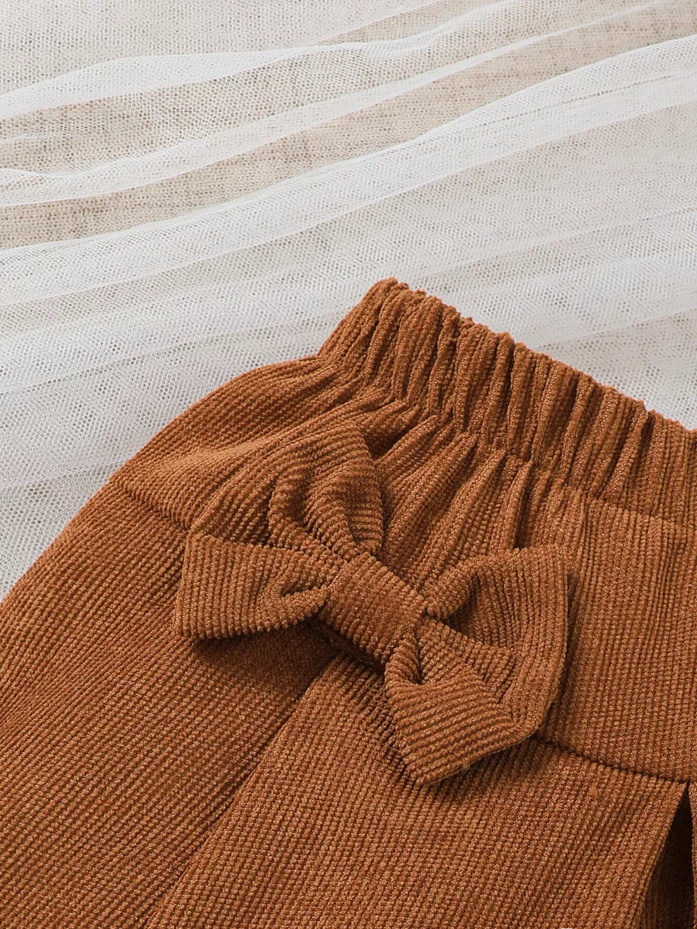 Brown corduroy baby skirt with elastic waist and bow detail.