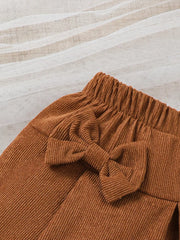 Brown corduroy baby skirt with elastic waist and bow detail.