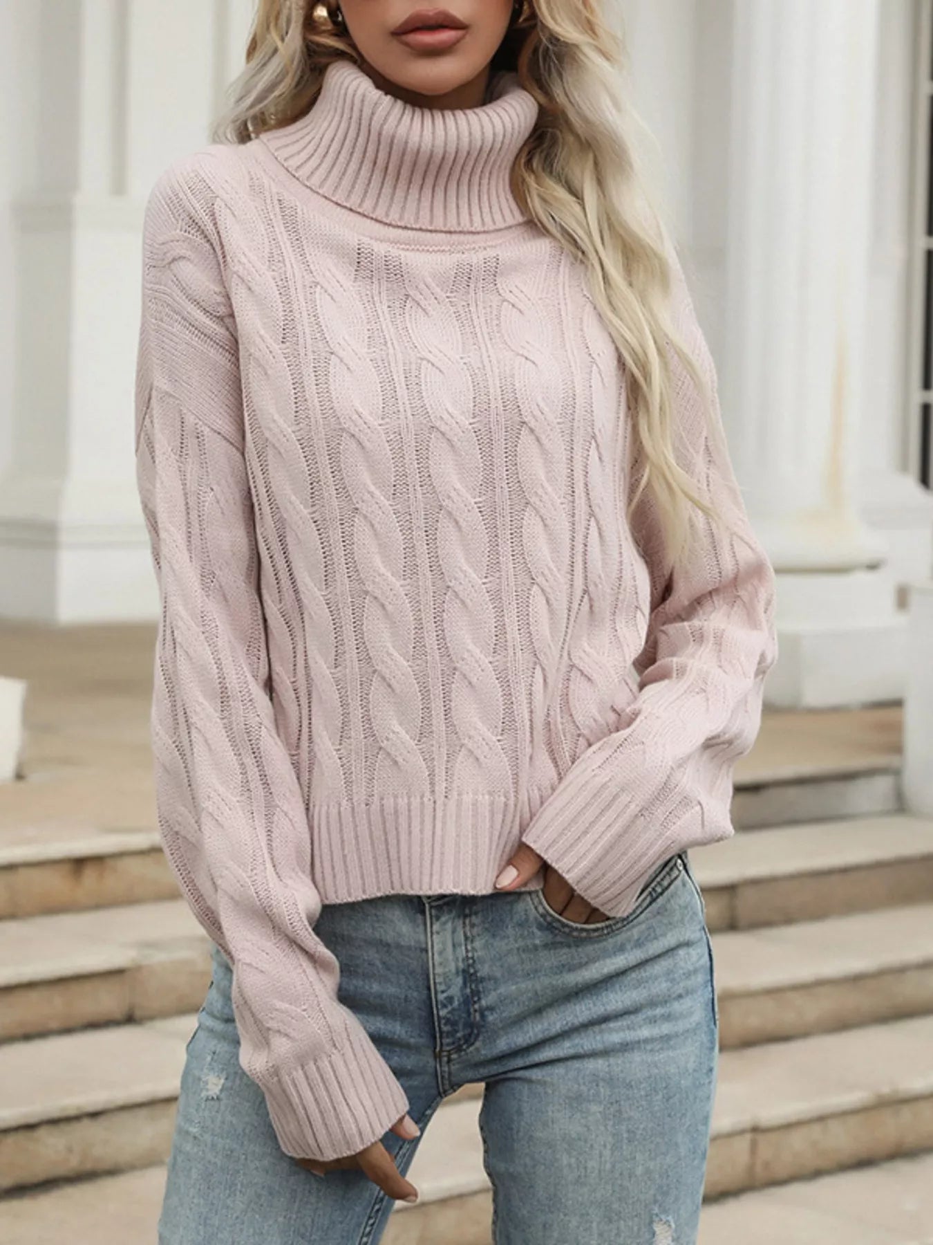 Pink cable knit turtleneck sweater with ribbed cuffs and hem.
