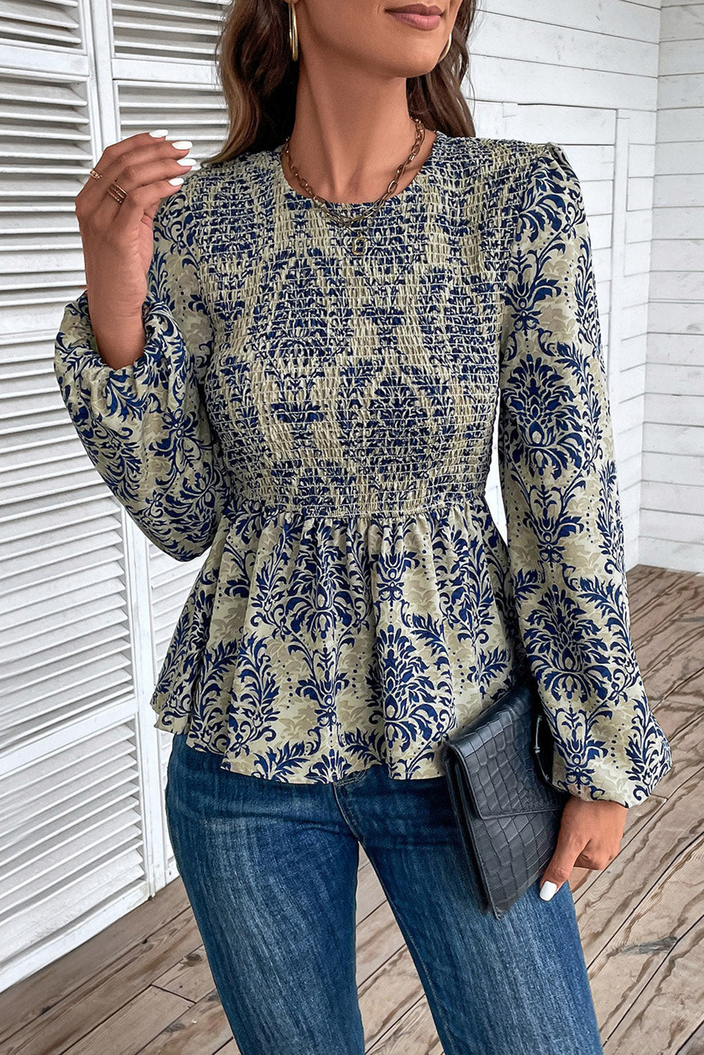 Navy damask print smocked peplum blouse with long sleeves and a round neckline.