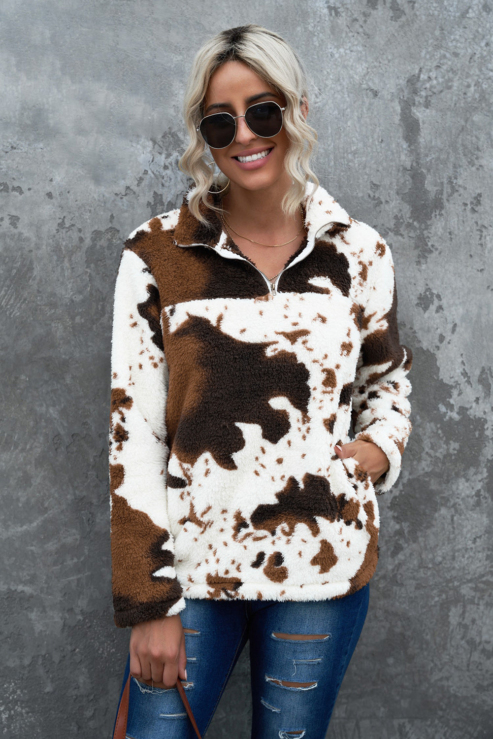 Cowhide sherpa quarter-zip pullover in white with brown cow print, featuring a fuzzy texture and a front pocket.