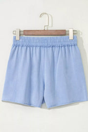Light blue cotton drawstring shorts with elastic ruffled waist and raw hem.