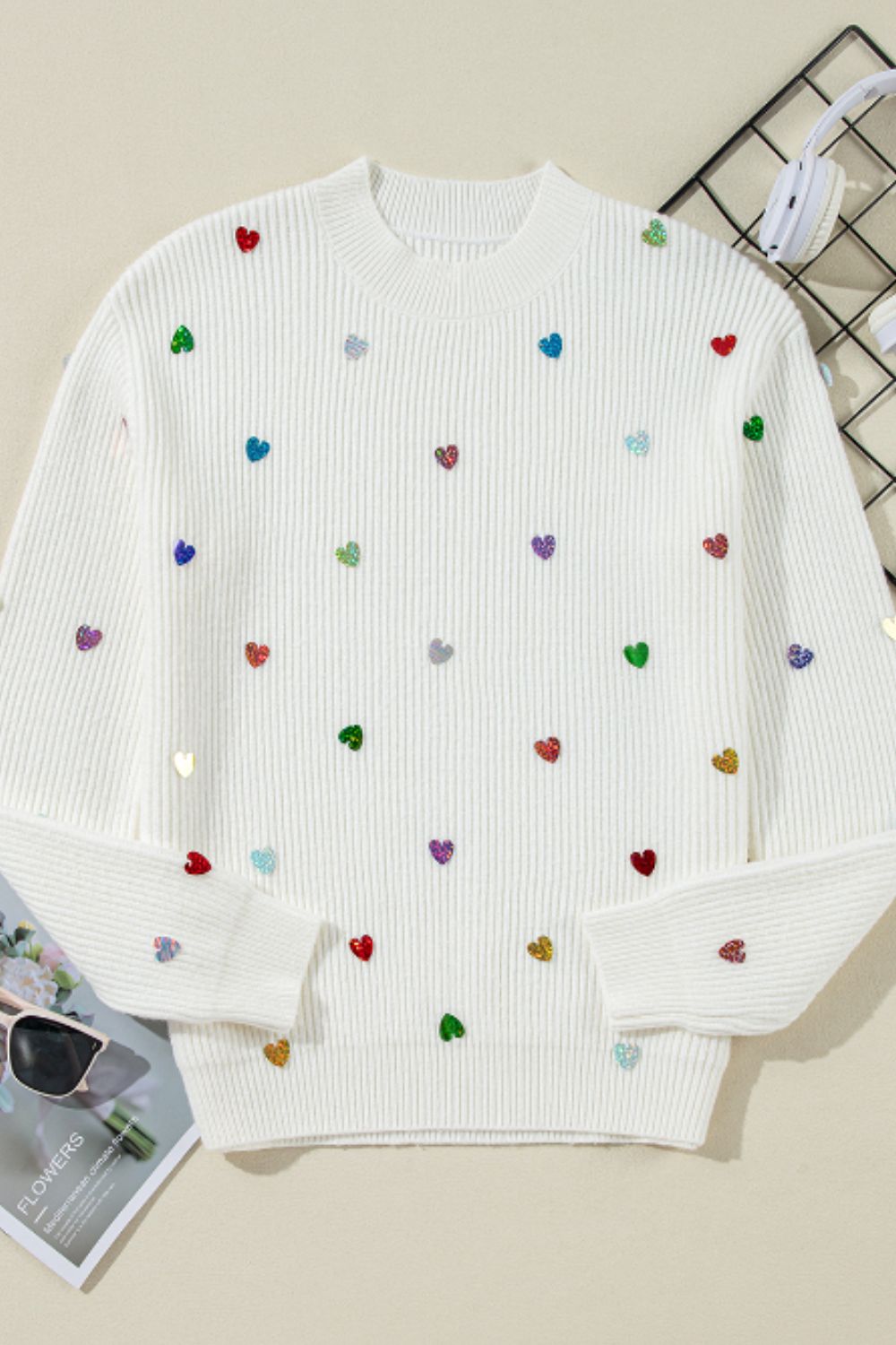 White ribbed knit sweater with colorful heart embellishments.