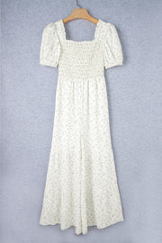 White floral smocked bodice wide-leg jumpsuit with puff sleeves and square neckline.