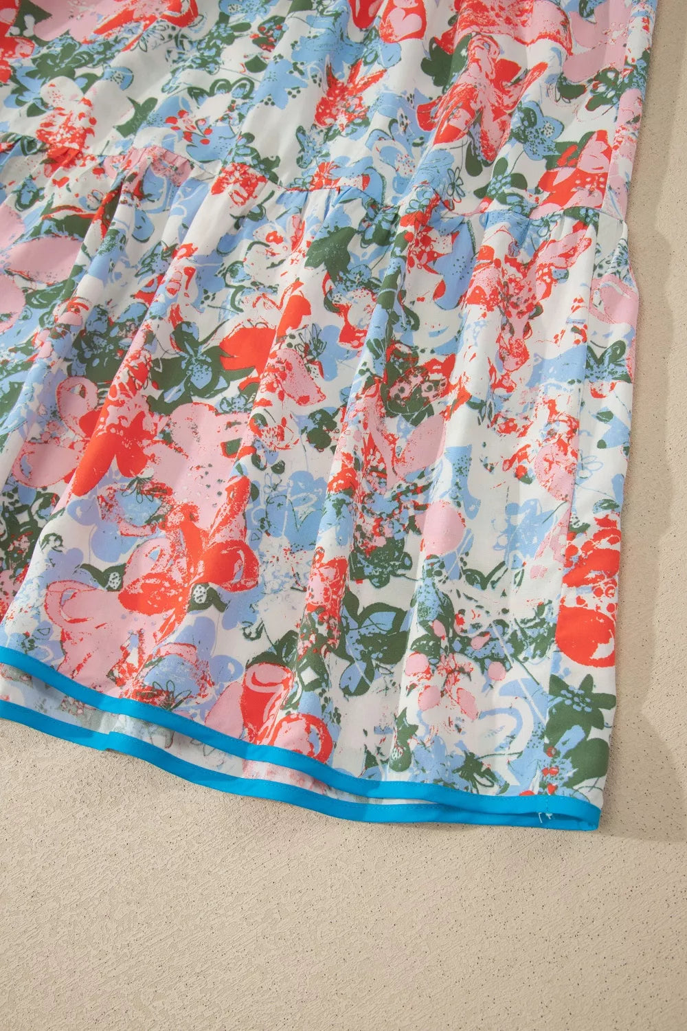 Maxi dress with vibrant floral print, tiered skirt, and blue trim detail.