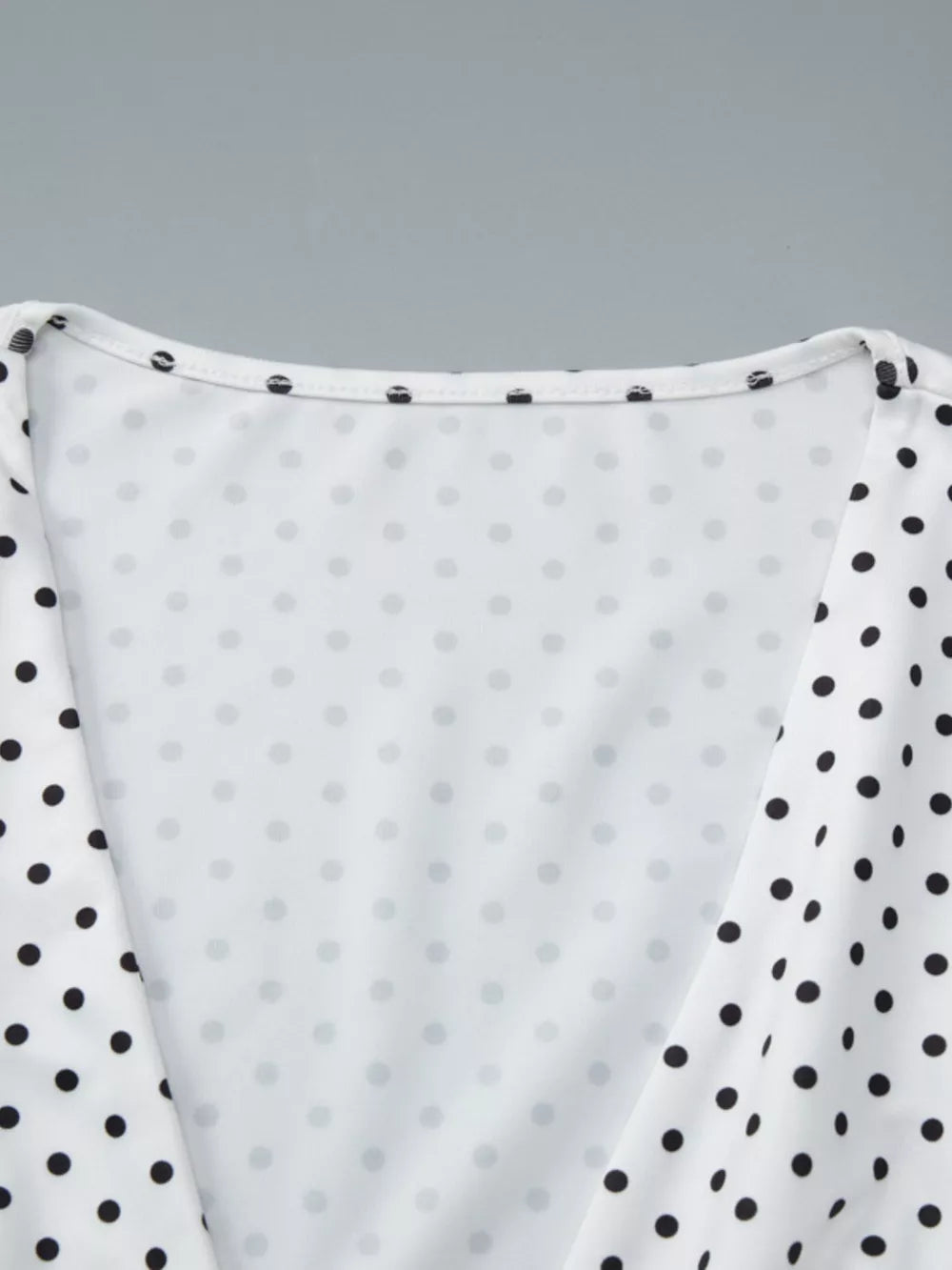 White polka dot ruched t-shirt with a v-neckline and short sleeves.