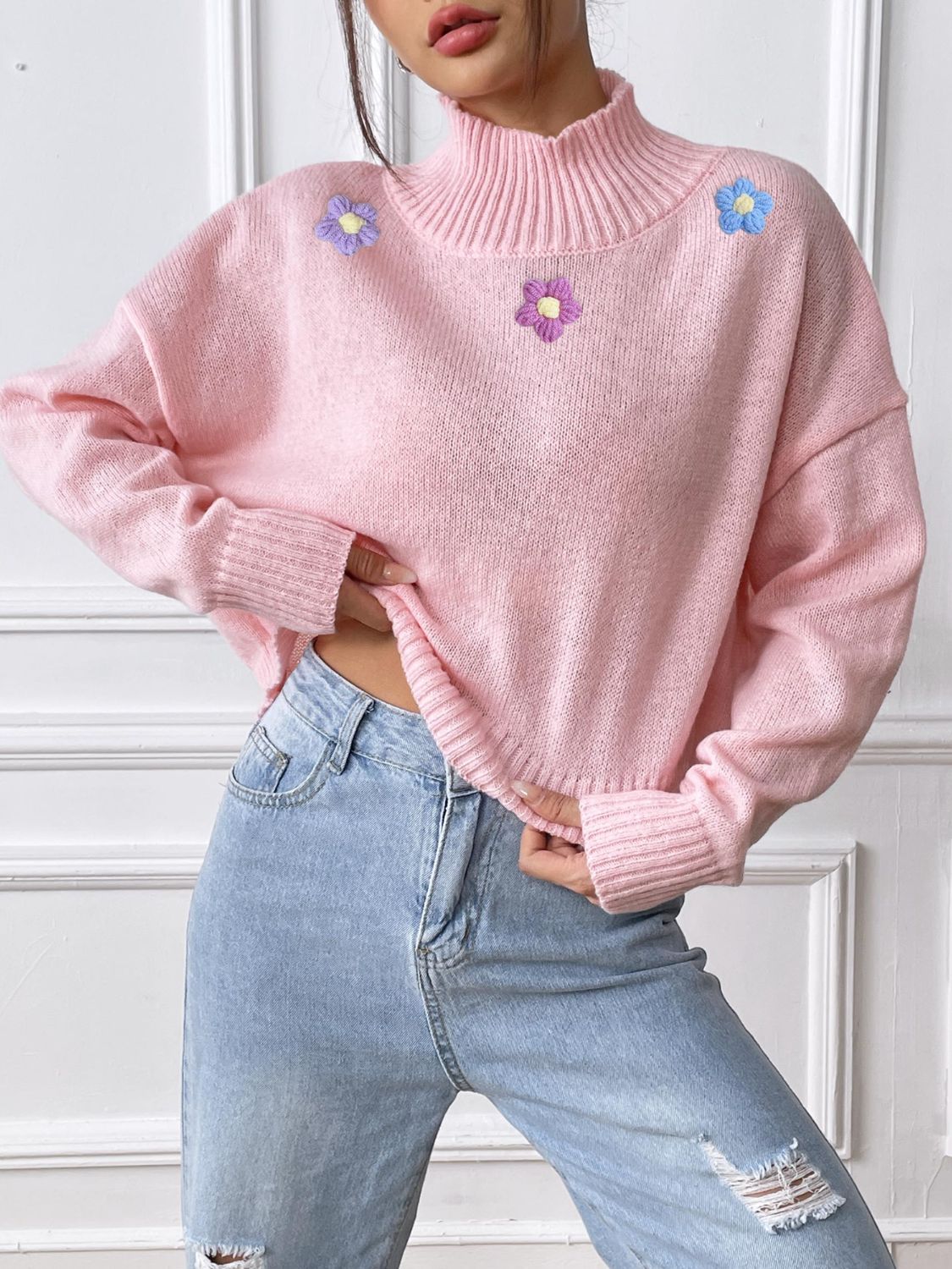 Blush pink cropped turtleneck knit sweater with embroidered floral details and ribbed cuffs.