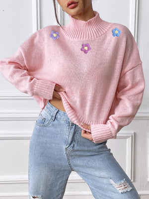 Blush pink cropped turtleneck knit sweater with embroidered floral details and ribbed cuffs.