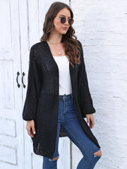 Black cable knit cocoon cardigan with V-neck and long sleeves.
