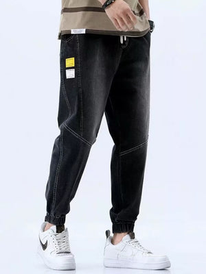 Men's black relaxed fit drawstring jeans with elastic cuffs and contrast stitching.