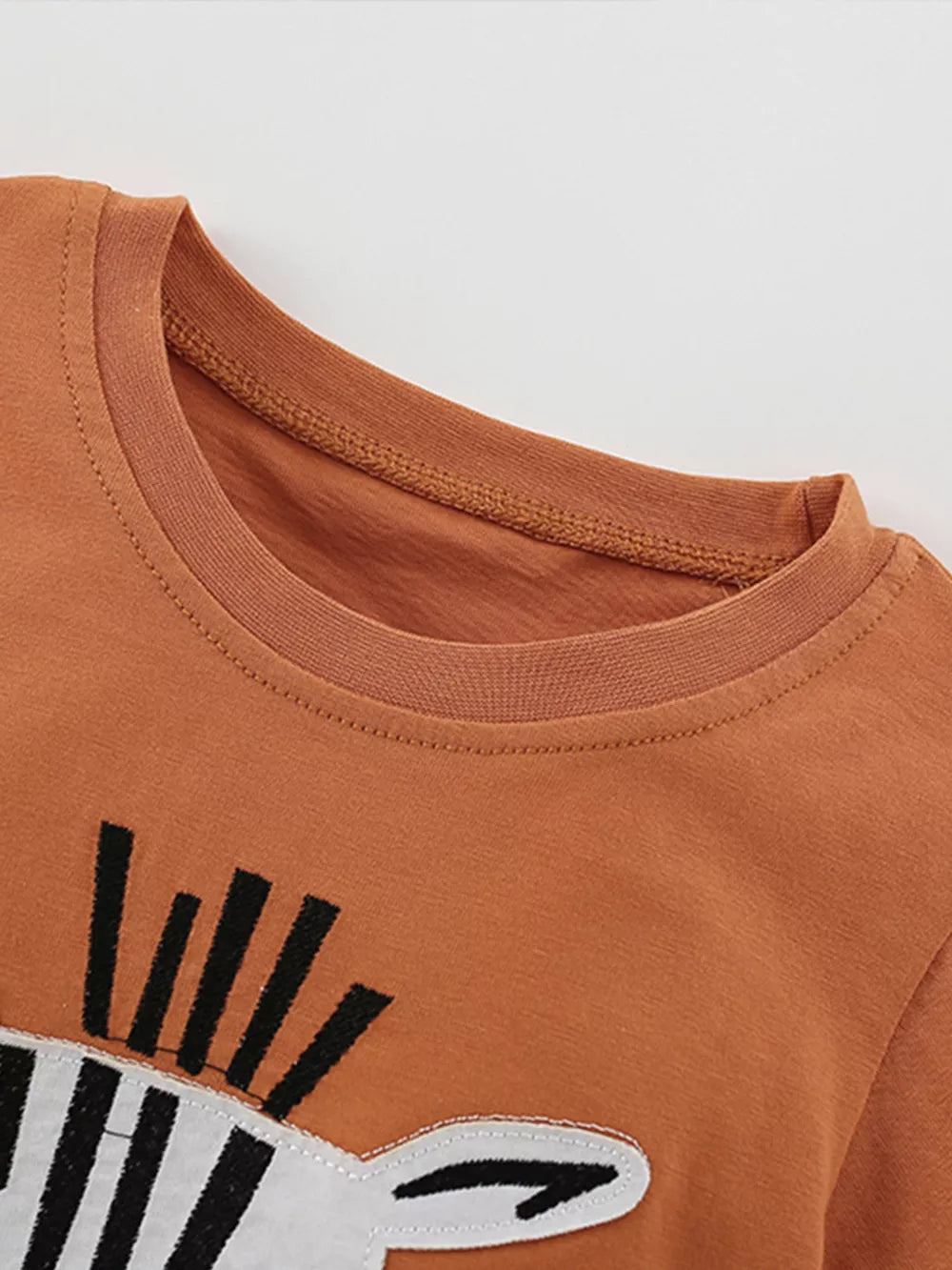Baby tee with zebra face graphic and crew neck in rust orange.