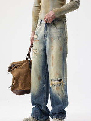 Men's distressed wide-leg jeans in faded blue denim with ripped details and a vintage wash.