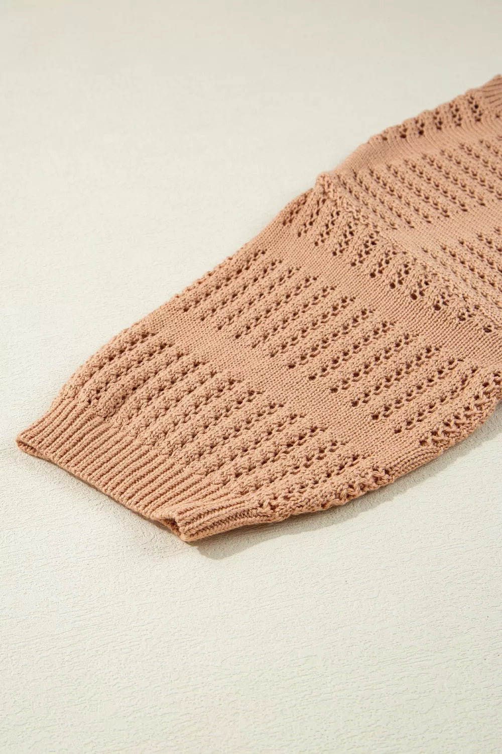 Peach openwork knit sweater with elbow sleeves and ribbed cuff.