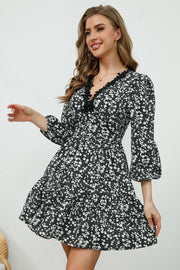 Black floral print mini dress with lace trim V-neck and bell sleeves.