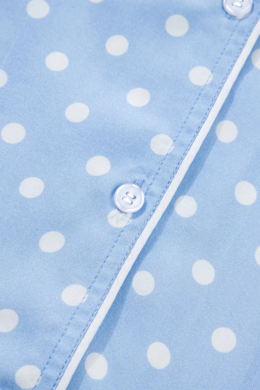 Blue polka dot viscose pajama top with white piping and button detail.