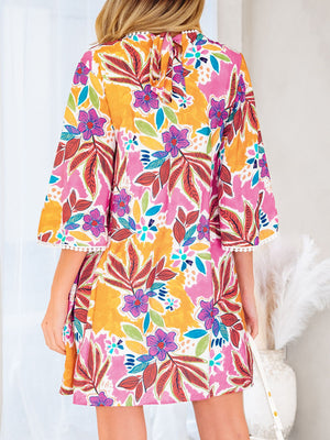 Print bell sleeve mini dress with colorful floral pattern and white pom-pom trim.