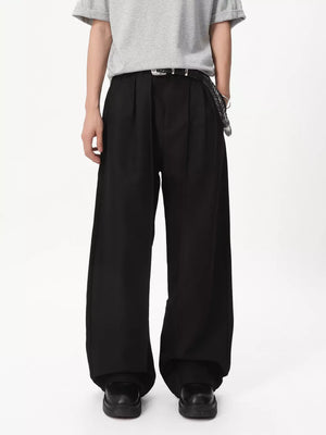 Black relaxed wide-leg pleated trousers with a braided belt and chain detail.